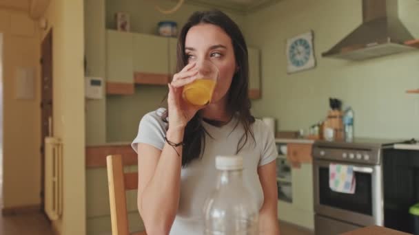 Jonge Vrouw Die Sinaasappelsap Drinkt Terwijl Keuken Zit — Stockvideo