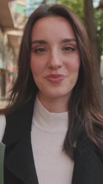 VERTICAL VIDEO, açık havada dururken gülümseyen genç bir kadının yakın çekimi
