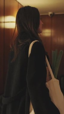 VERTICAL VIDEO, eve dönen genç bir kadın. Arka plan