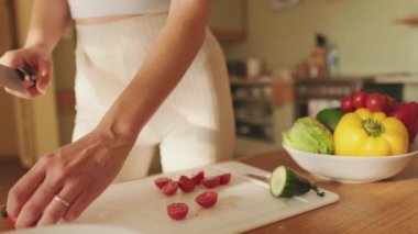 Genç bir kadının ellerinde domates keserken, evde salata yaparken.