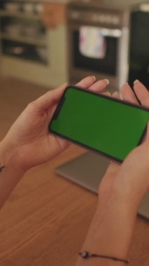 VERTICAL VIDEO, evdeki cep telefonu yeşil ekran krom anahtarı kullanan genç kadının ellerinin yakın çekimi