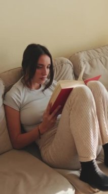 VERTICAL VIDEO, Evdeki kanepede oturan kitap okuyan genç kadın
