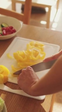 VERTICAL VIDEO, mutfakta evde salata yapan biber kesen genç kadınların yakın çekimi