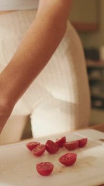 VERTICAL VIDEO, mutfakta salata yapan genç bir kadının ellerini keserken yakın çekim.