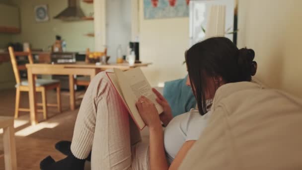 Młoda Kobieta Czyta Książkę Siedząc Kanapie Domu — Wideo stockowe