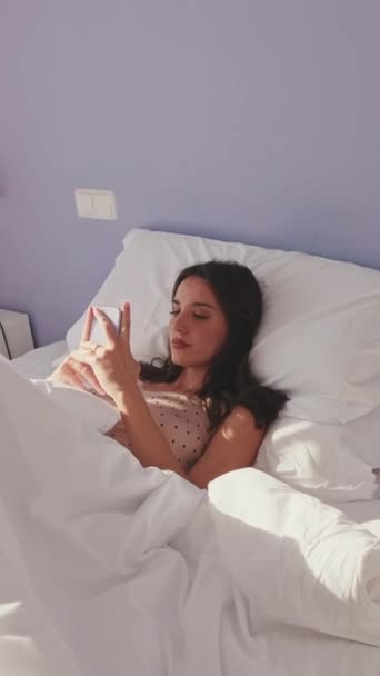 Vertical Video Akıllı Telefonunu Kullanan Yatakta Yatan Genç Bir Kadın — Stok video