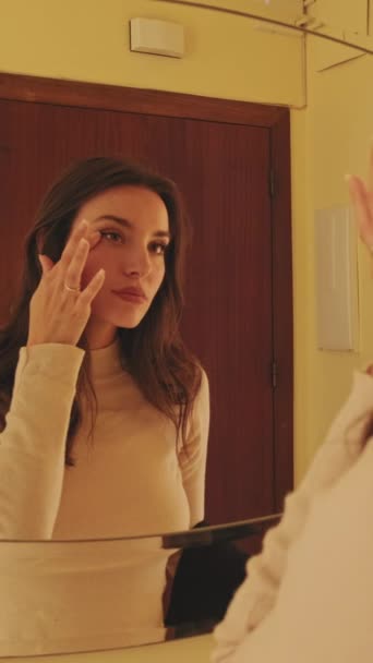 Vertisk Video Ung Kvinna Justera Makeup När Står Framför Spegeln — Stockvideo