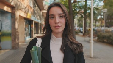 Dışarıda dikilip kameraya bakarken genç bir kadının yakın çekimi.