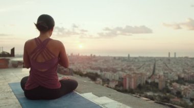 Vücut kıyafetli genç bir kadın güneş doğarken yoga yapıyor. Arka plan