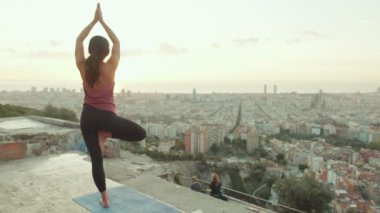 Kız şafak vakti gözetleme noktasında yoga yapıyor.