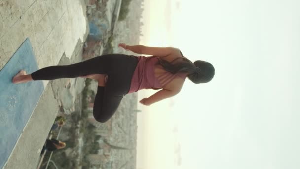 垂直ビデオ 女の子の練習ヨガは夜明けに展望台で一本足で立つ — ストック動画
