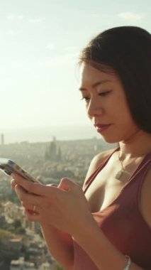 Yakın çekim, mutlu atletik kadın gözetleme noktasında dururken cep telefonu kullanıyor.