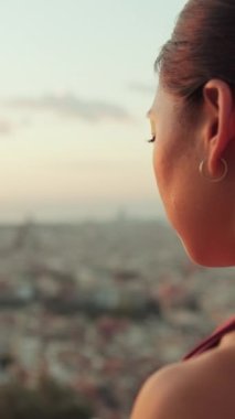 Yakından bakınca, vücut kıyafetli genç bir kadın güneş doğarken yoga pratiği yapıyor. Kız nilüfer pozisyonunda otururken ellerini kaldırır. Arka plan