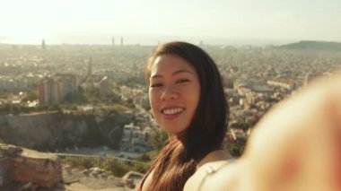 İzleme noktasında dururken cep telefonundan selfie çeken mutlu atletik kadın.