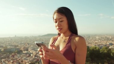 İzleme noktasında dururken cep telefonu kullanan mutlu atletik kadın.