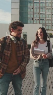 Happy diverse students chatting and laughing walk together down the street to the university