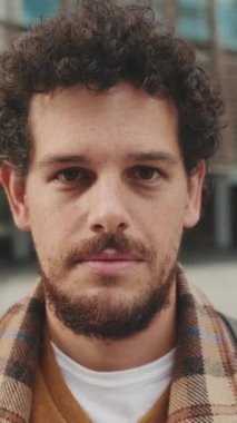 Close up, guy student stands outside the university building looks at the camera and smiles