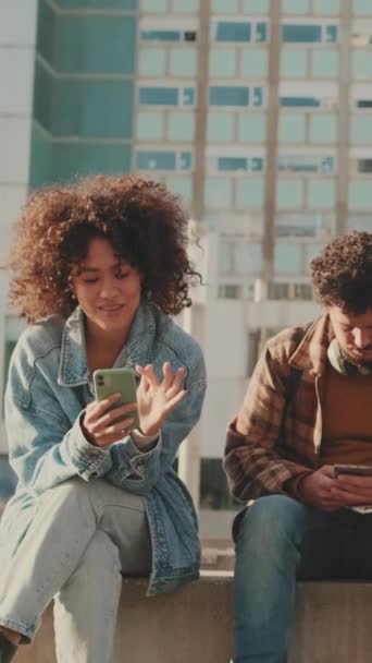 Couple Students Using Mobile Phones Talking While Sitting — Vídeo de stock