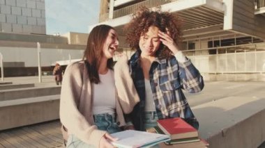 Girls share news and have fun sitting next to the university building