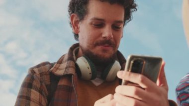Portrait of a happy guy typing a social media message on his mobile phone