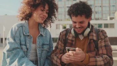 Close-up of happy student couple talking to each other using mobile phone