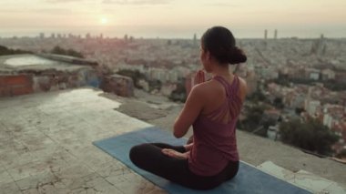 Vücut kıyafetli genç bir kadın güneş doğarken yoga yapıyor. Arka plan