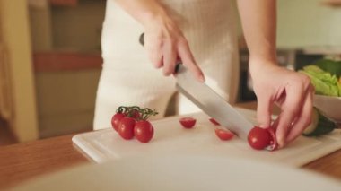 Genç bir kadının ellerinde domates keserken, evde salata yaparken.