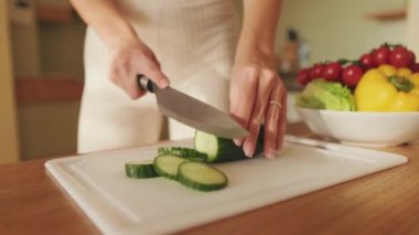 Mutfakta salatalık kesen genç bir kadının ellerini yakından çek. Yukarıdan görüntüle