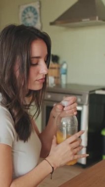 VERTICAL VIDEO, Young woman about to drink juice in the kitchen