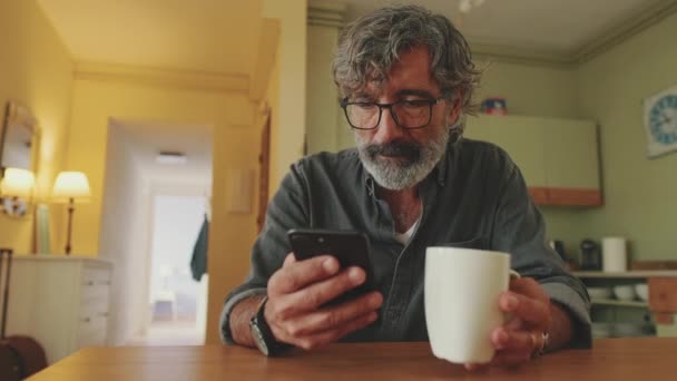 Elderly Disappointed Man Drinks Coffee Mug Uses Mobile Phone Home — Video Stock