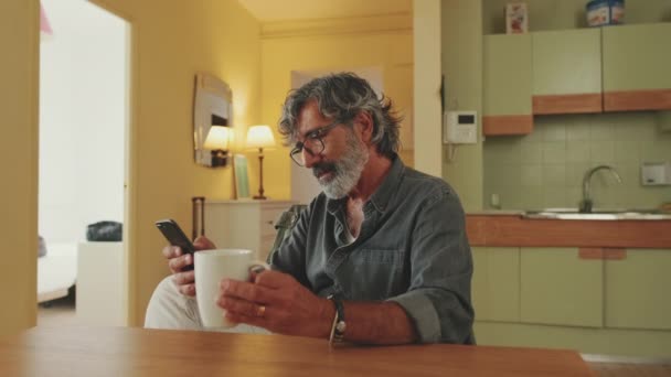 Elderly Man Carefully Reads Message His Smartphone Drinks Coffee While — Vídeos de Stock