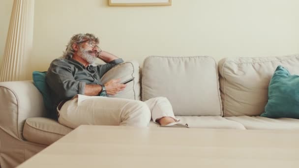 Muž Středního Věku Relaxuje Gauči Zatímco Pomocí Smartphonu Textovat — Stock video