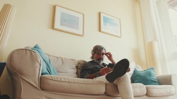 Starší Pozitivní Muž Používající Mobilní Telefon Když Sedí Doma Pohovce — Stock video