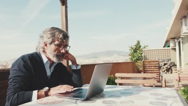 Hombre Mediana Edad Trabajando Ordenador Portátil Mientras Está Sentado Balcón — Vídeo de stock