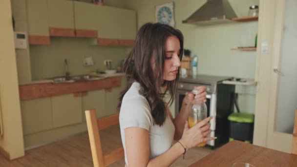 若い女性は約台所でジュースを飲むために — ストック動画