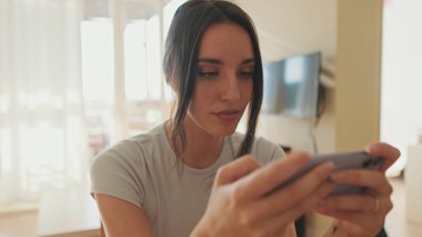 Dairede otururken cep telefonu kullanan genç bir kadın.