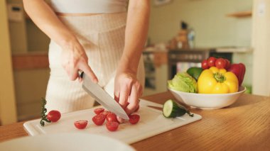 Genç bir kadının ellerinde domates keserken, evde salata yaparken.