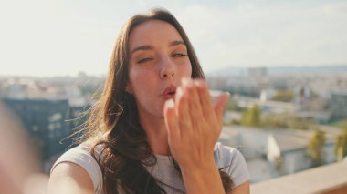 Genç bir kadının balkonda dururken selfie çekerken el sallaması işareti çekerken.