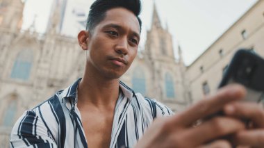 Basamaklardaki genç turist, arka planda otururken cep telefonu kullanıyor