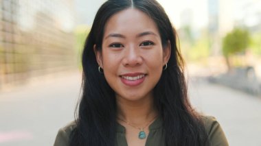 Kameraya bakıp gülümseyen genç kızın yakın çekimi.