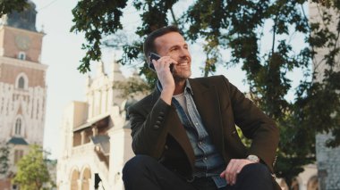 Kasabanın arka planında cep telefonuyla konuşan orta yaşlı bir adam.