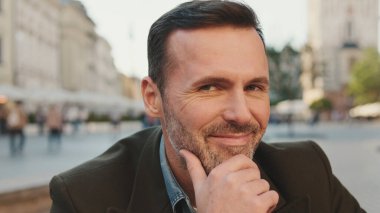 Kameraya bakıp gülümseyen bir adam.