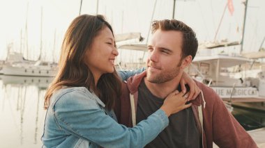 Romantik çift yat arka planında iskelede oturuyor.