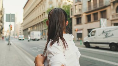 Yolun kenarında dururken cep telefonu kullanan genç bir kadın. Kız etrafına bakıyor.