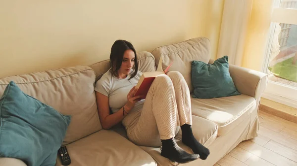 Jovem Mulher Lendo Livro Sentado Sofá Casa — Fotografia de Stock