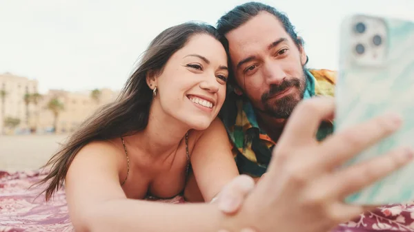 ビーチで携帯電話を使ってビデオ通話をする男と女 — ストック写真