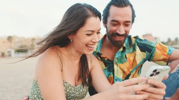 Молода Пара Використовує Мобільний Телефон Сидячи Пляжі Фоні Будівель Крупним — стокове фото