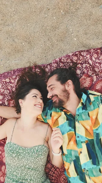 年轻夫妇在海滩上躺在毯子上享受彼此的交流 顶部视图 — 图库照片