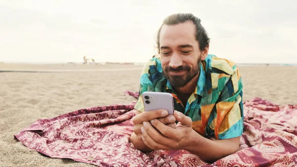 Sorrindo Homem Jaz Praia Com Smartphone Suas Mãos — Fotografia de Stock