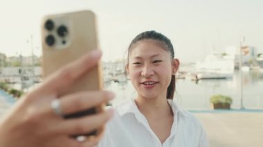 Young woman making video call with mobile phone on seascape background